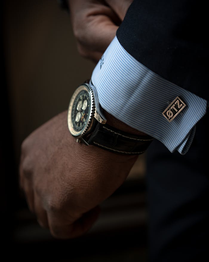 Close-up of a sophisticated black wristwatch and cufflink on a man's wrist, showcasing elegance and style.